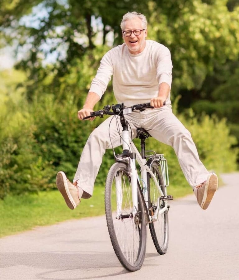 Happy older man riding a bicycle outdoors