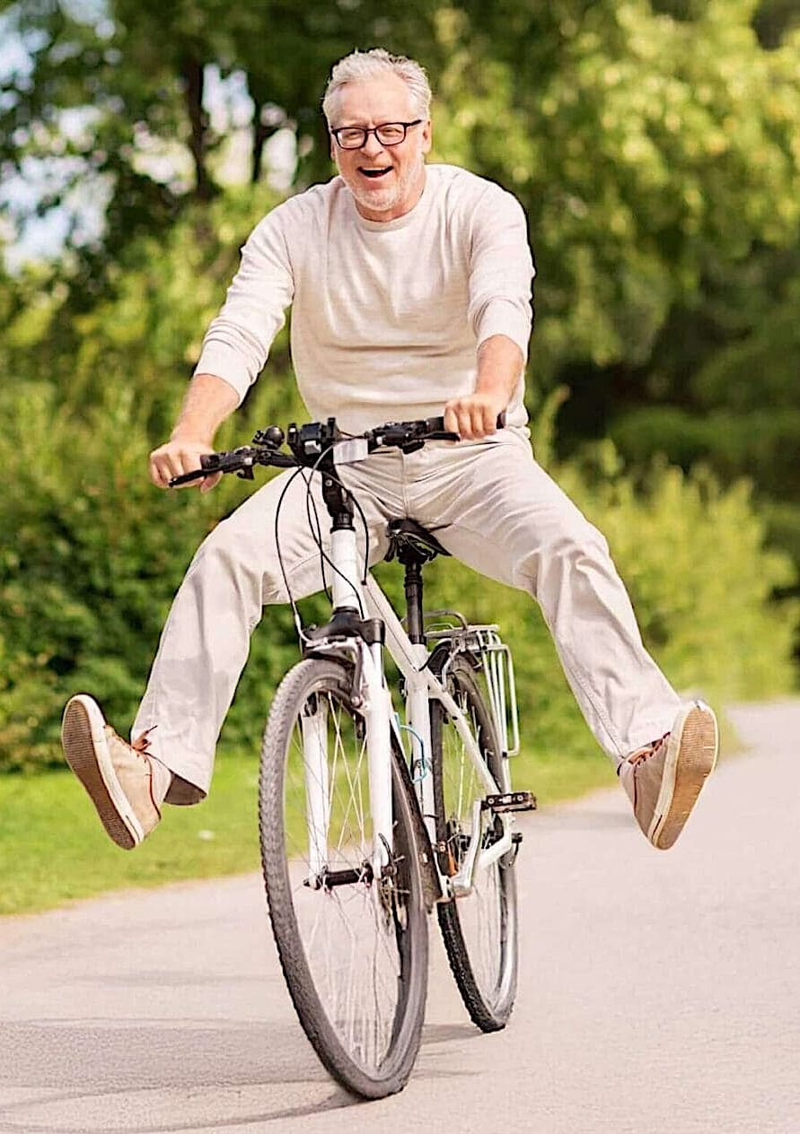 Happy older man riding a bicycle outdoors
